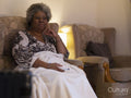 Woman sitting under blanket and watching TV