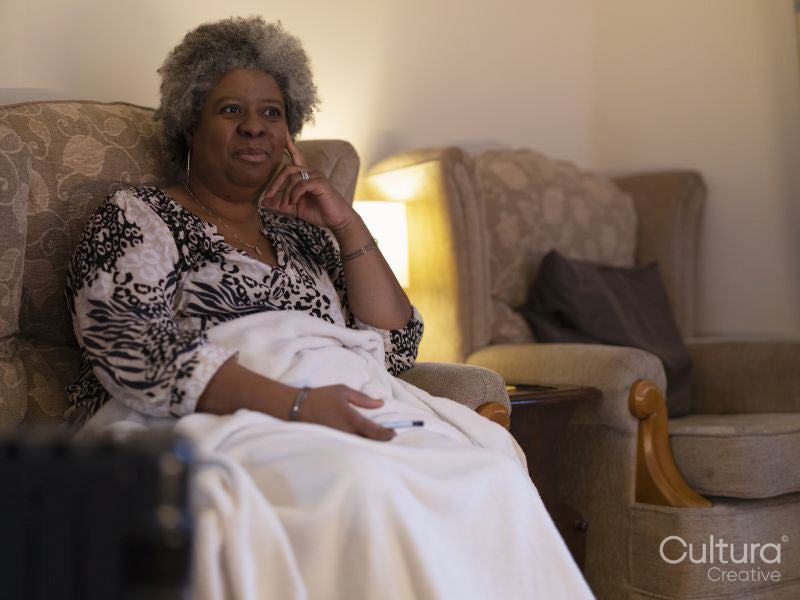 Woman sitting under blanket and watching TV