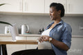 Smiling pregnant woman using laptop in kitchen