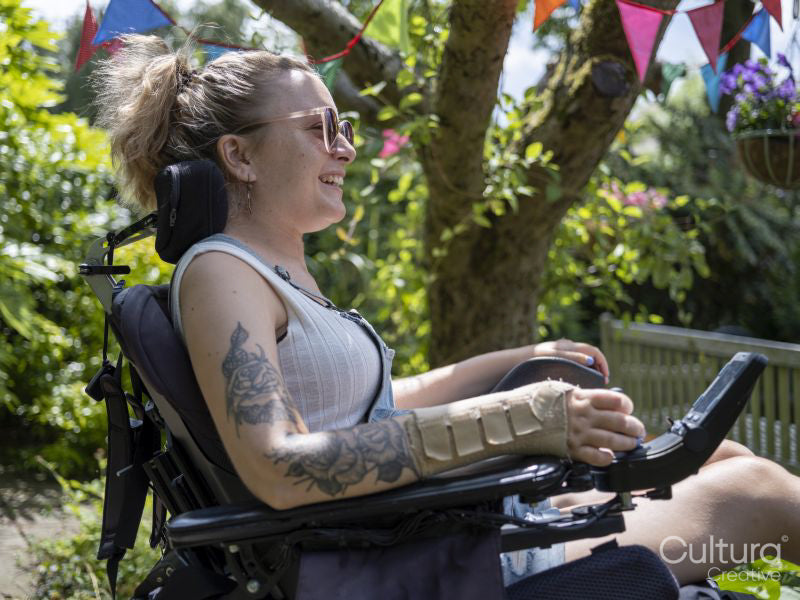 Woman in electric wheelchair sunbathing in back yard