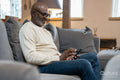 Senior man sitting on sofa and using phone