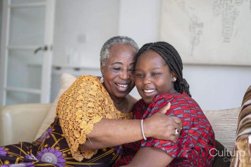 Smiling senior woman hugging teenage granddaughter at home