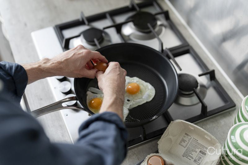 Close-up of man breaking egg into pan