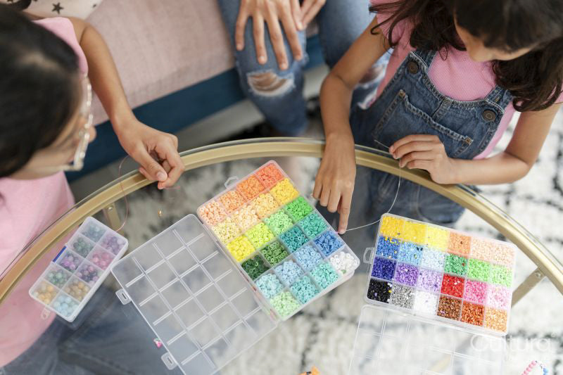 Sisters playing with beads in living room