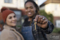 Two young women standing in front of house and holding key