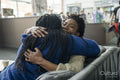 Mother with daughter embracing while sitting on sofa