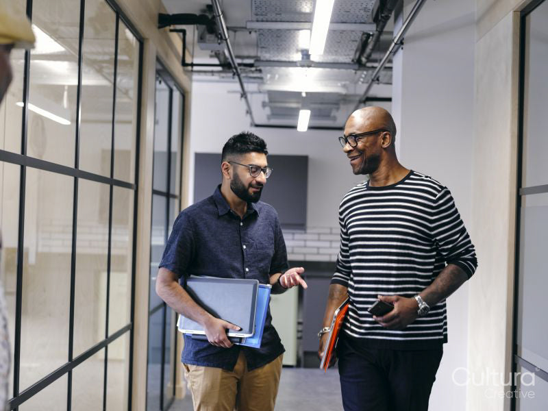 Two men talking in office hallway