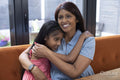Smiling mother embracing daughter at home