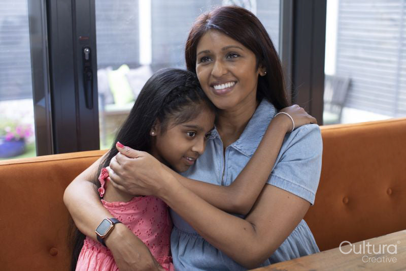 Smiling mother embracing daughter at home