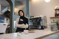 Portrait of young woman in hijab working in cafe