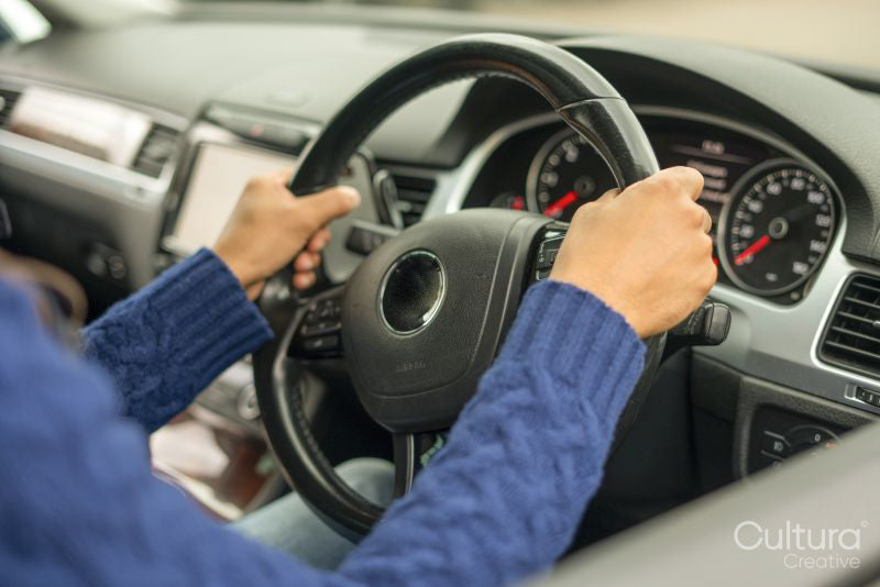 Mans hands on a steering wheel in car