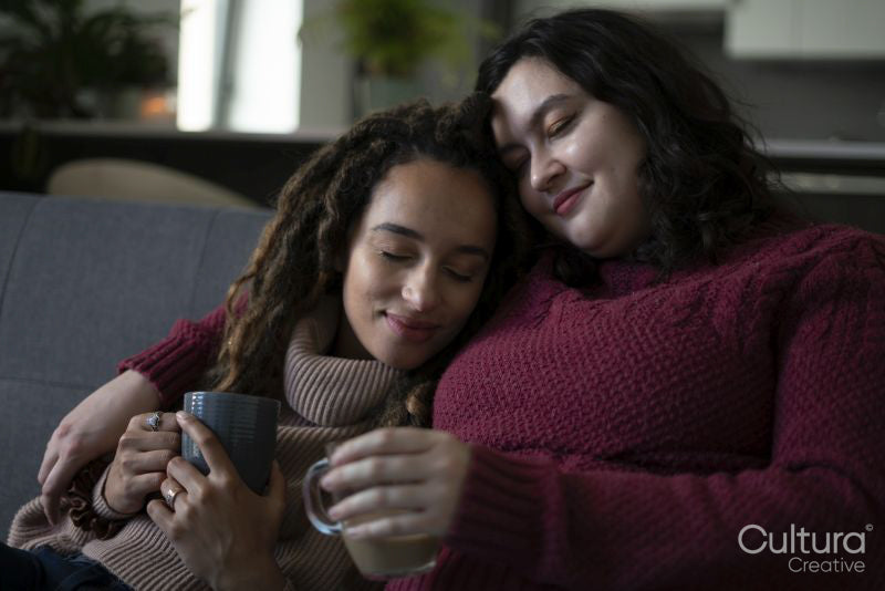 Two women sitting on sofa and embracing