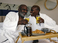Mature couple enjoying breakfast on bed in hotel room