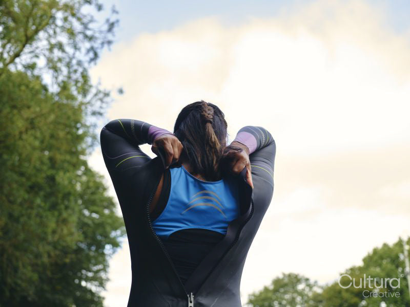 Rear view of woman putting on wetsuit