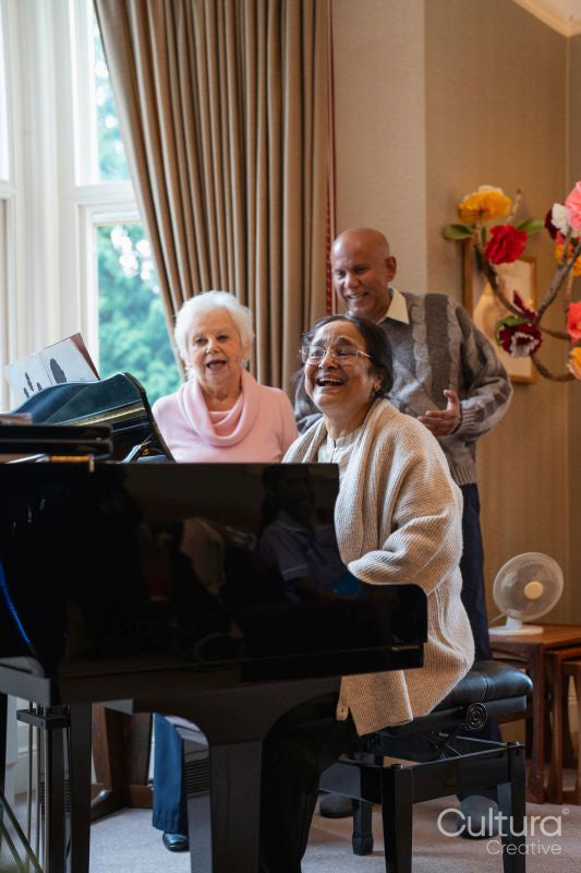 Senior people singing at piano in nursing home