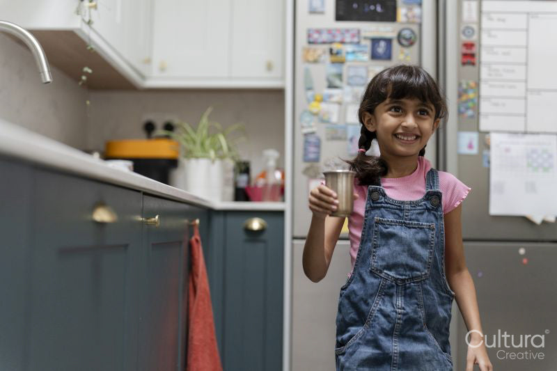 Little girl holding mug in kitchen