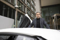 Mature man leaning against luxury car