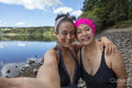 Portrait of smiling women in swimsuits on rocky lakeshore, Yorkshire, UK