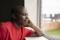 Teenage boy looking through window at home