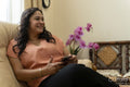 Mature woman using smart phone while sitting on sofa at home