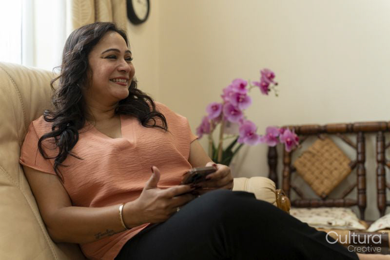 Mature woman using smart phone while sitting on sofa at home