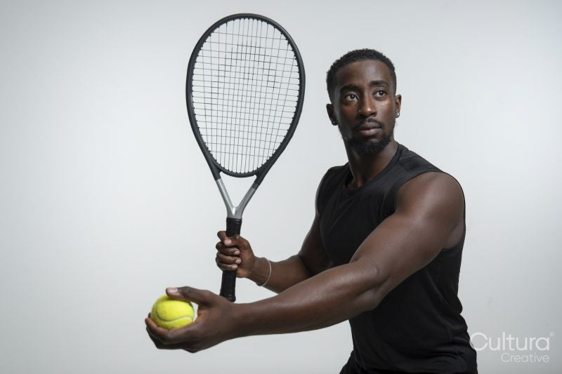 Portrait of man holding tennis ball and racket