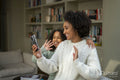 Smiling mother and daughter having video call at home