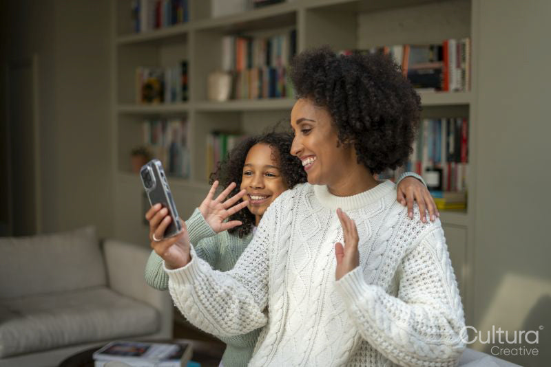 Smiling mother and daughter having video call at home