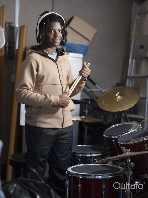 Portrait of teenage boy standing next to drums