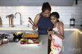 Smiling mother and daughter looking at smart phone in kitchen