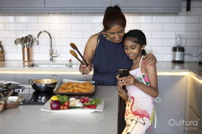 Smiling mother and daughter looking at smart phone in kitchen