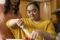 Woman with down syndrome daughter preparing food in kitchen