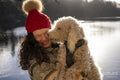 Young woman holding dog at lake