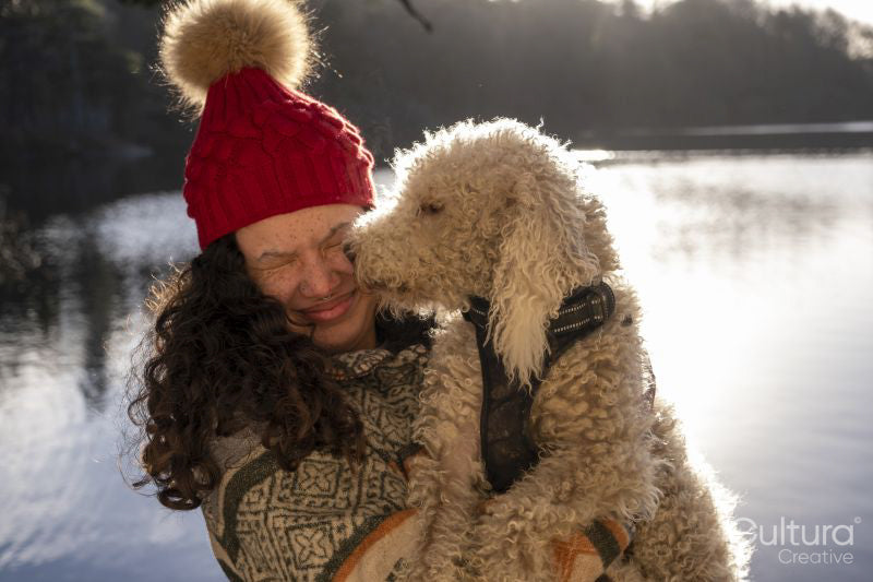 Young woman holding dog at lake