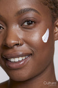Close-up of smiling woman with face cream on cheek