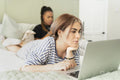 Two young women on bed using mobile devices