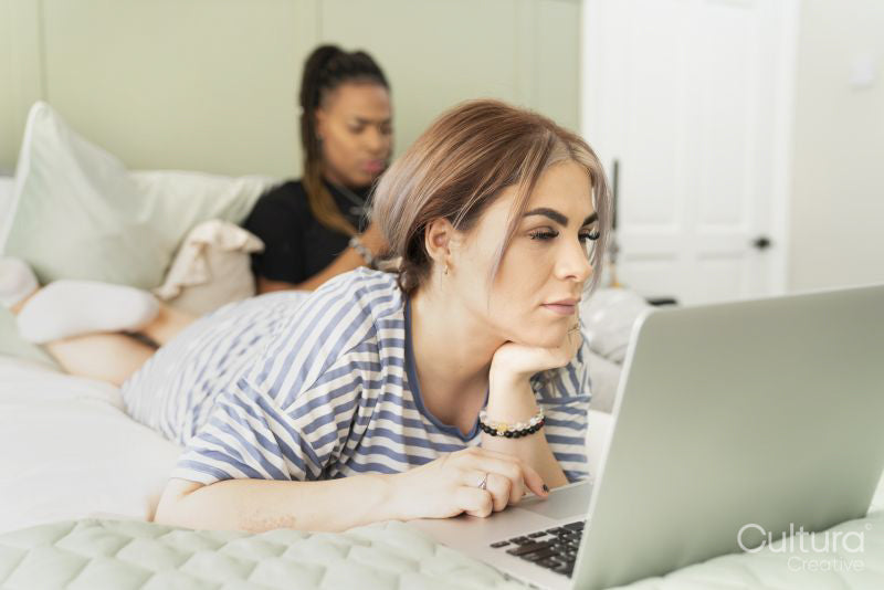 Two young women on bed using mobile devices