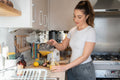 Woman in kitchen, pouring freshly made smoothie
