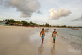 Indonesia, Lombok, Surfers walking on beach at sunset