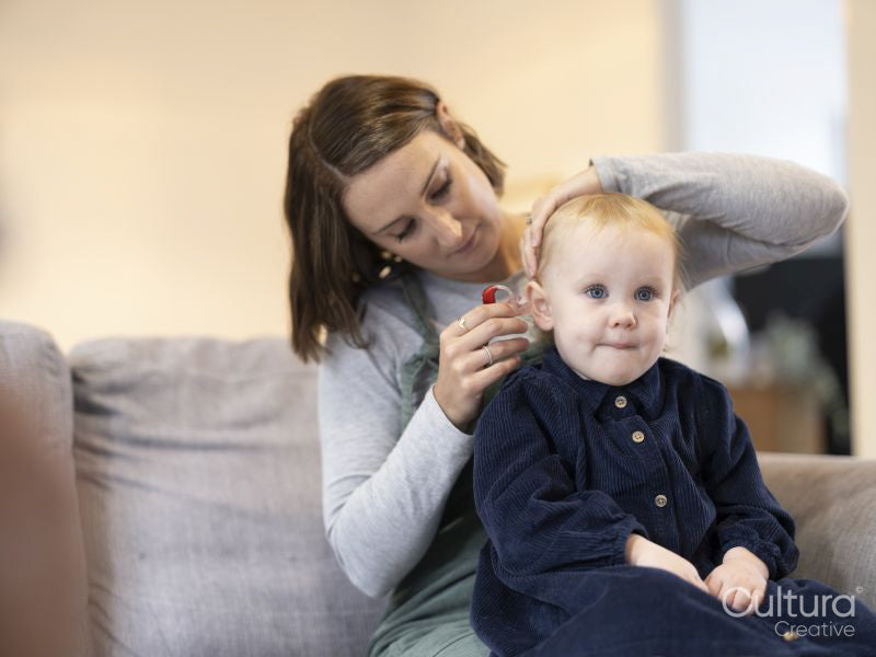 Mother helping daughter with hearing aid