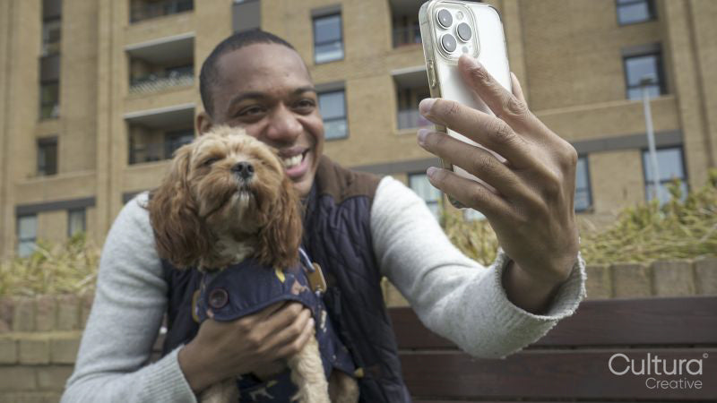 Man with dog using smartphone to take selfie