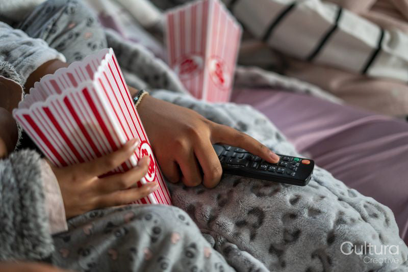 Close-up of sisters holding remote control and popcorn