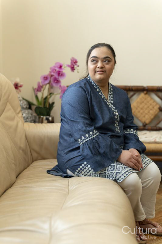 Portrait of young woman with down syndrome sitting on sofa at home