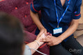 Nursing assistant taking pulse from senior woman at nursing home