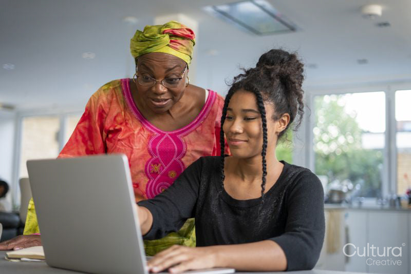 Teenage girl and senior woman looking at laptop