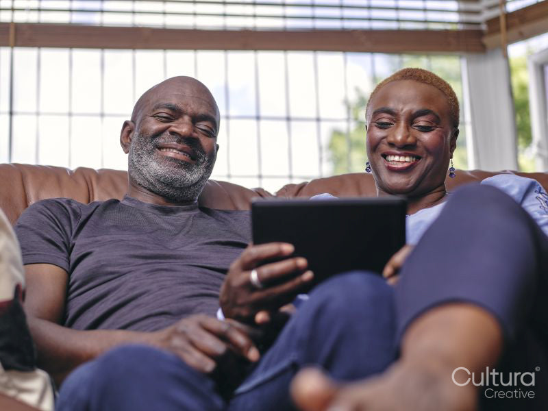 Couple sitting on sofa and using digital tablet