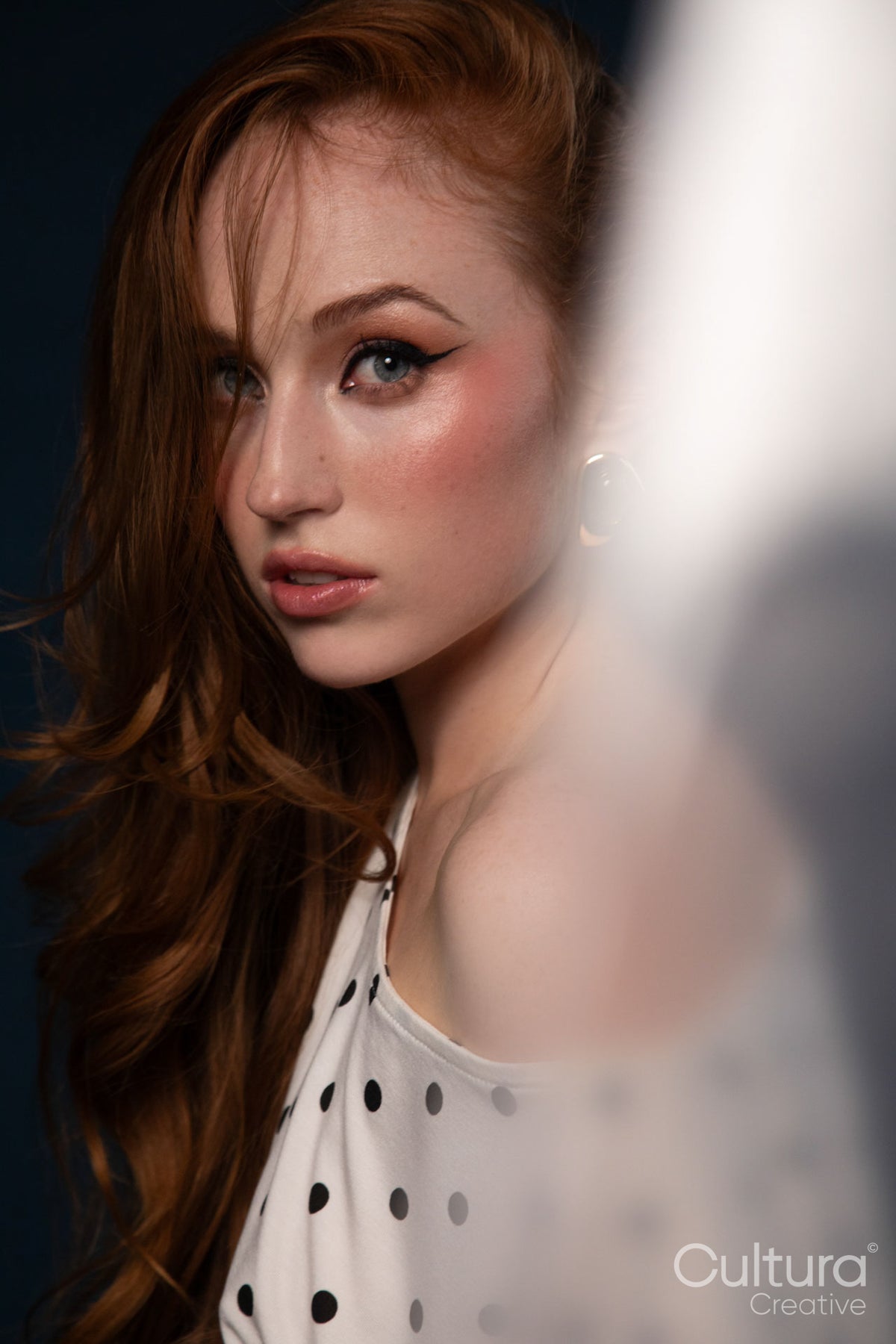 Studio portrait of a woman in a polka dot top with windswept hair