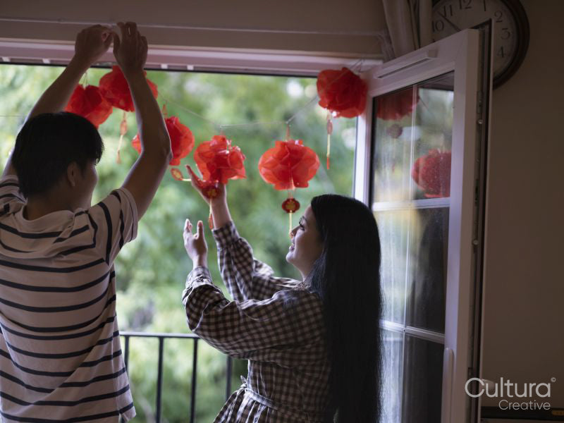 Couple hanging traditional Chinese decorations on window