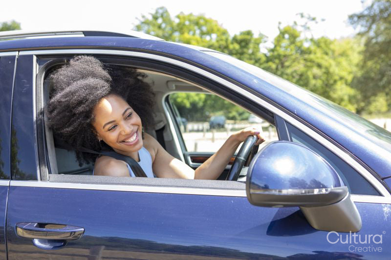 Young woman driving car, leaning out of window