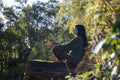 Woman meditating on log in forest